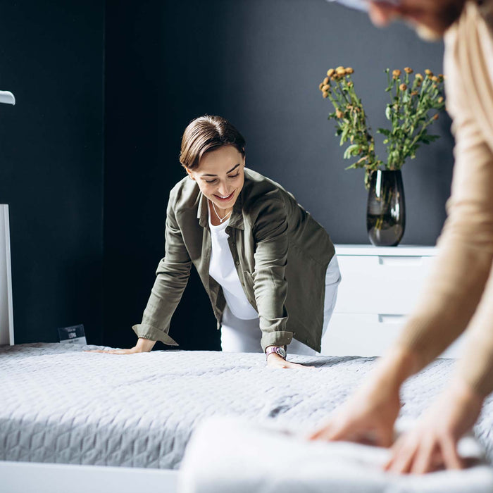 Two Women Making Separate Beds. Mattress Cover on Bed