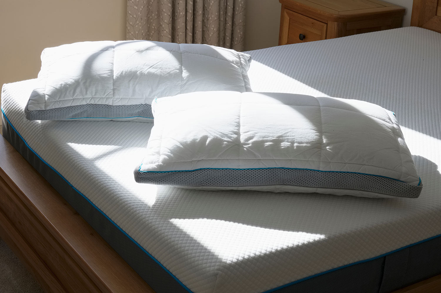 Two Pillows laid Diagonally near foot of bare Mattress, Sunlight shining on pillows through window