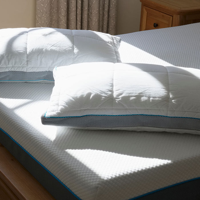 Two Pillows laid Diagonally near foot of bare Mattress, Sunlight shining on pillows through window