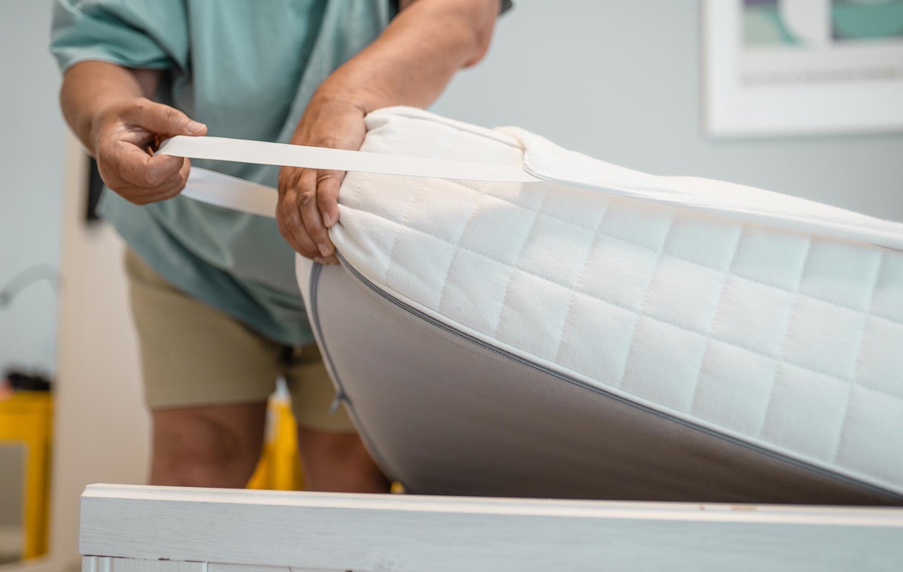 A man attaching a mattress protector on a mattress. 