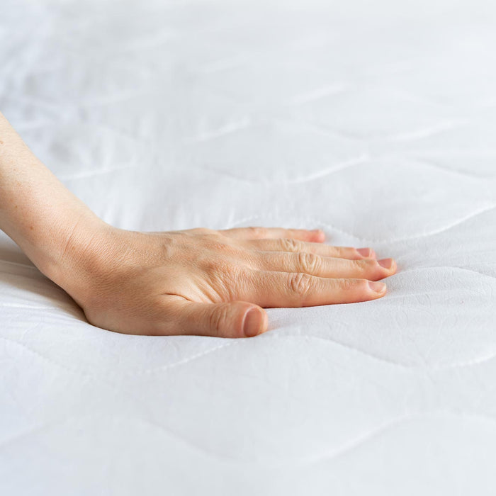 A hand pressed on a mattress.