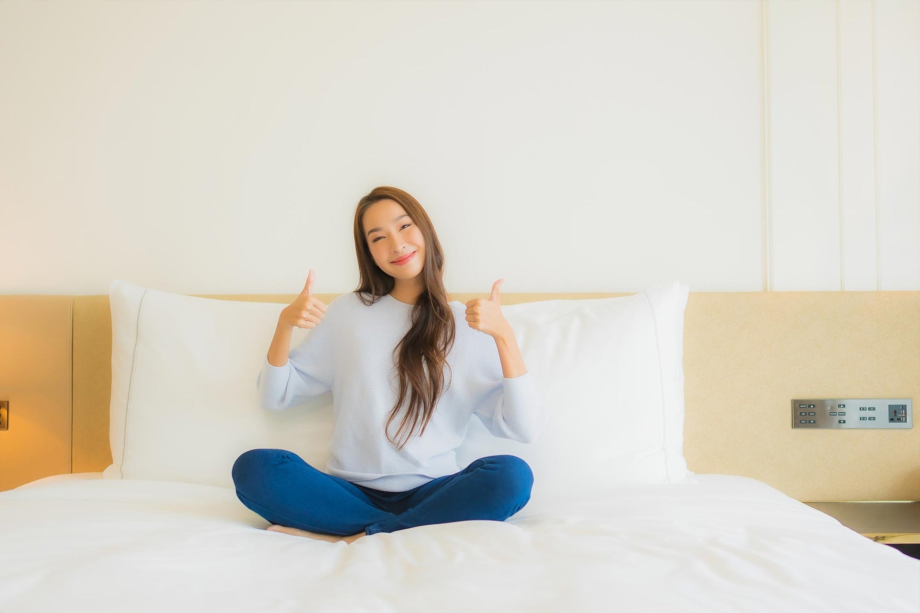 Woman on a bed smiling. Mattress and bed in the image.